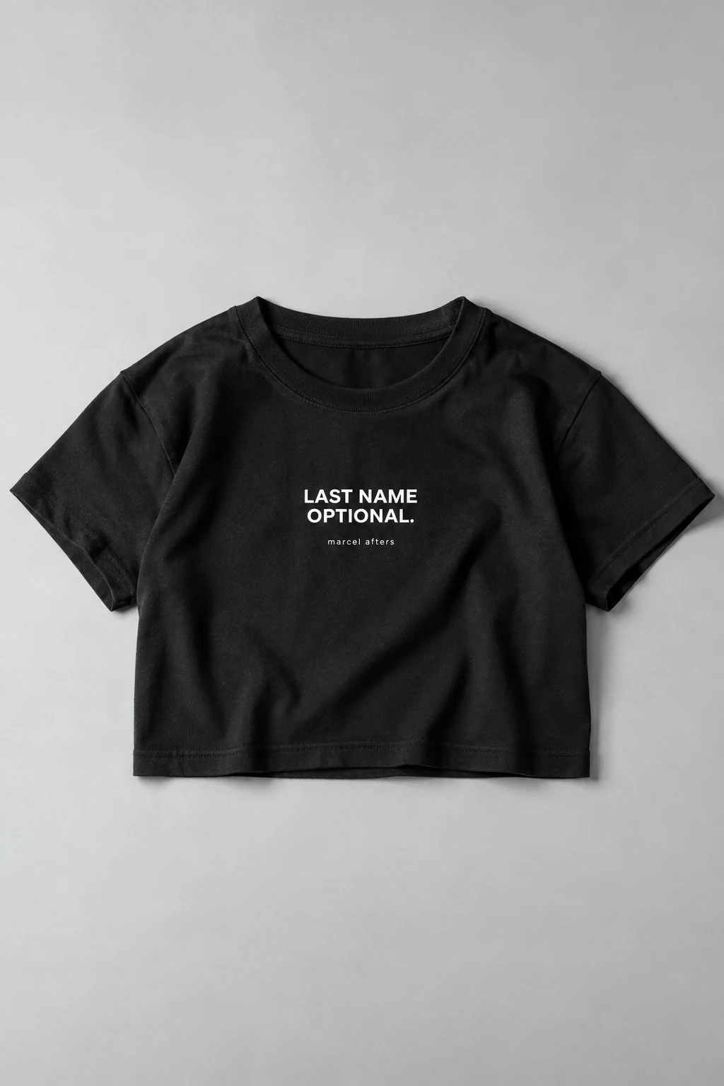 Black Last Name Optional shirt concept, laid flat with the white slogan and Marcel Afters signature fully visible.