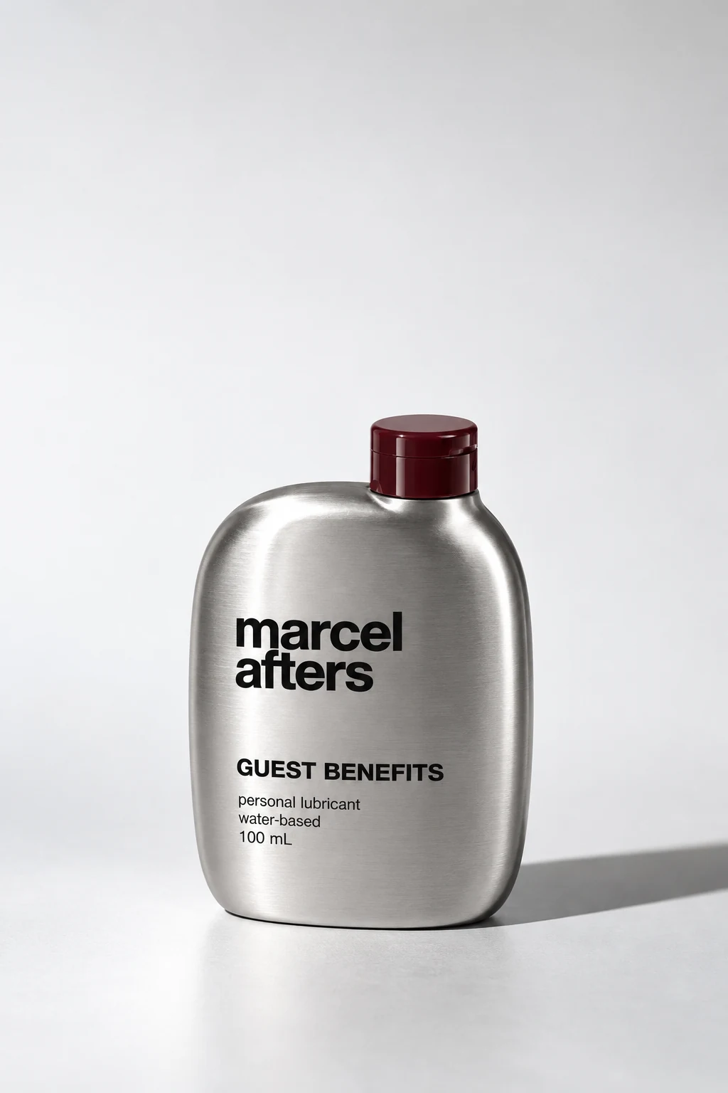 Guest Benefits concept: a brushed silver Marcel Afters bottle with a burgundy cap, labelled water-based personal lubricant, 100 mL.