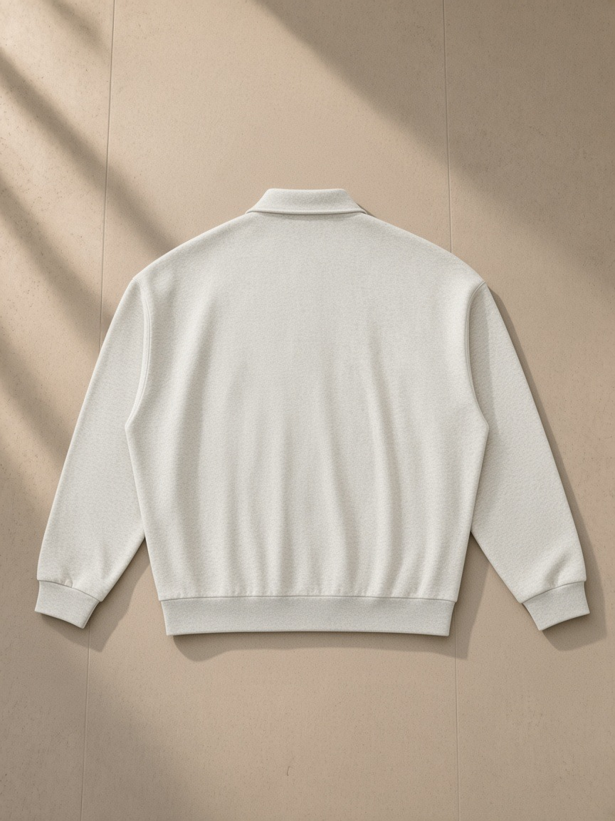 Heavyweight fleece polo sweatshirt in Oat Gray, laid flat on pale limestone, back view