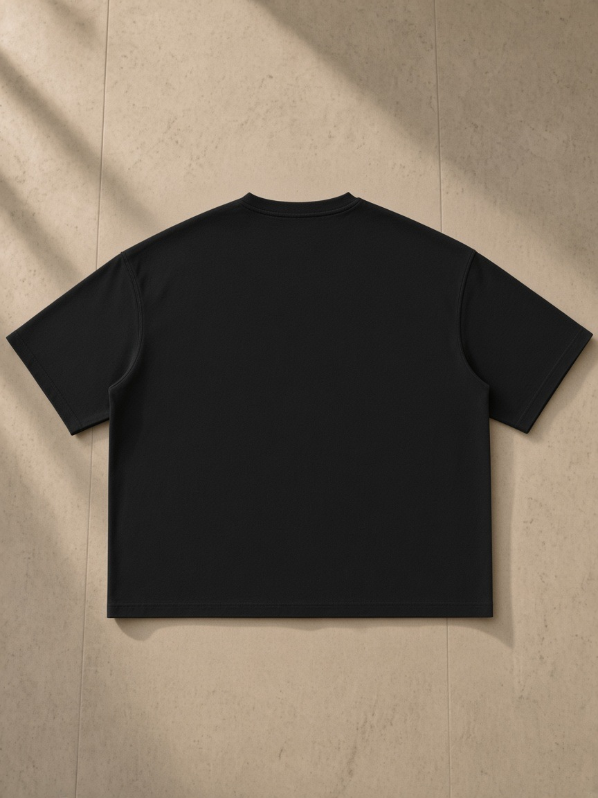 Washed Rolled Hem Half Sleeve T-Shirt in Black, laid flat on pale limestone, back.