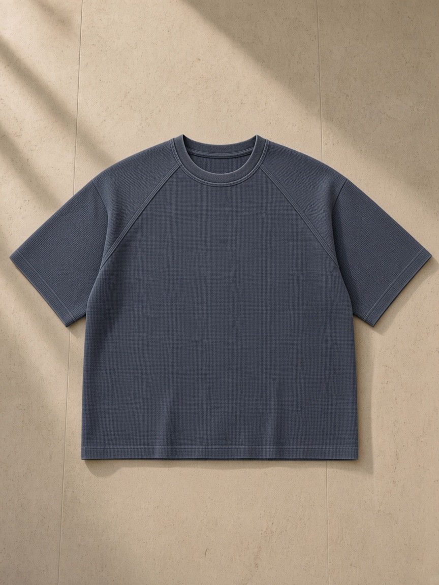 Unisex mineral wash boxy waffle t-shirt in Gray Blue, laid flat on pale limestone