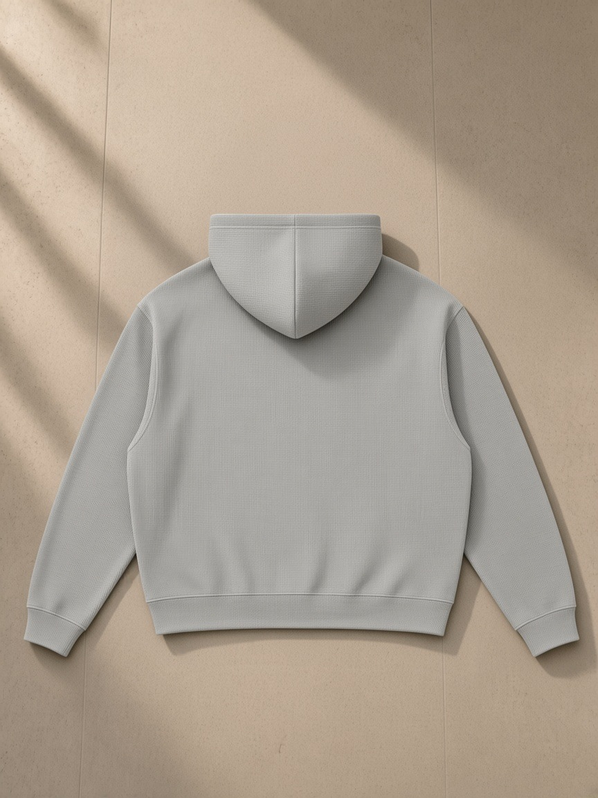 Unisex waffle boxy full zip hoodie in Light Gray, laid flat on pale limestone, back view
