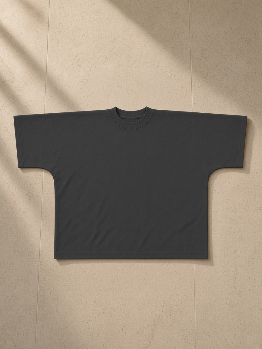 Oversized one-piece boxy t-shirt in Dark Gray, laid flat on pale limestone