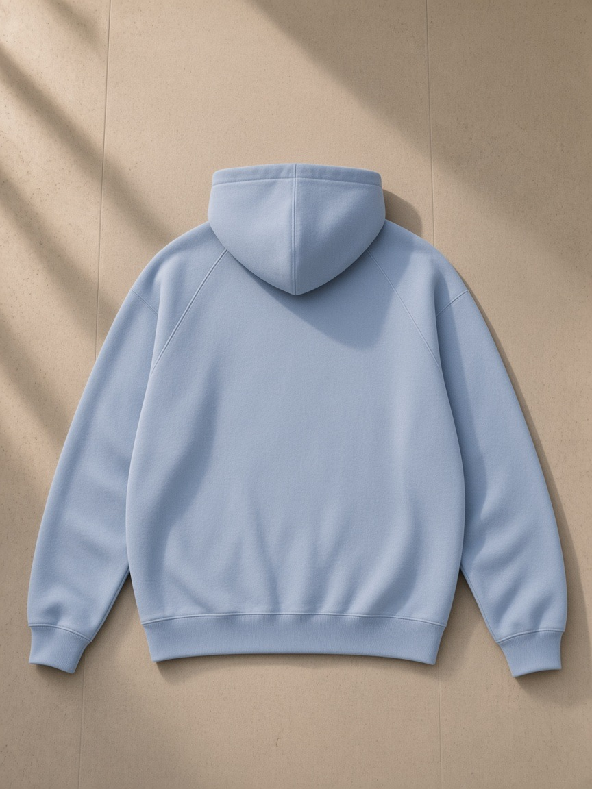 Oversized Raglan Pullover Hoodie in Light Blue, laid flat on pale limestone, back view