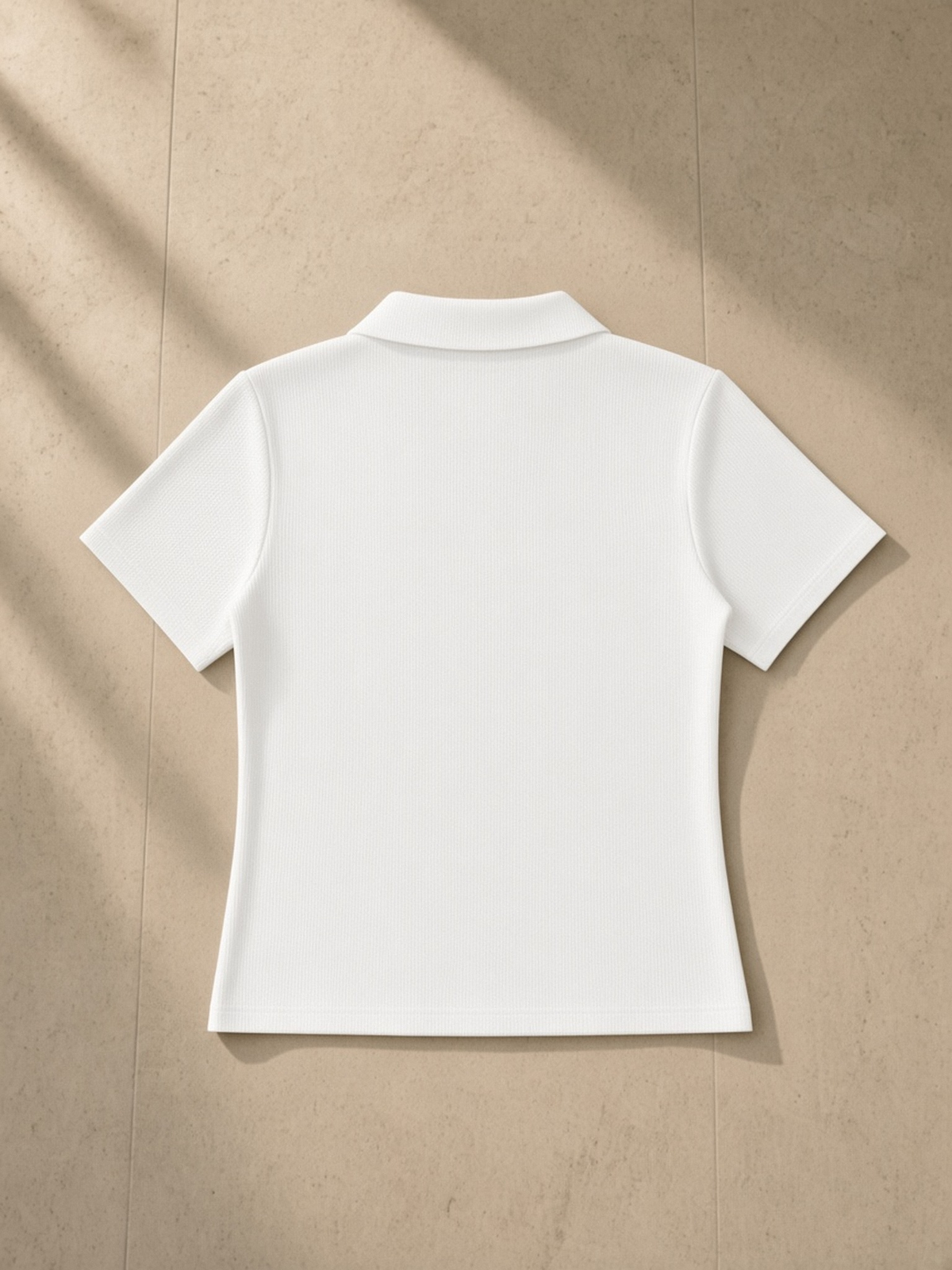 Bodycon Short Sleeve Polo Shirt in White, laid flat on pale limestone, back.