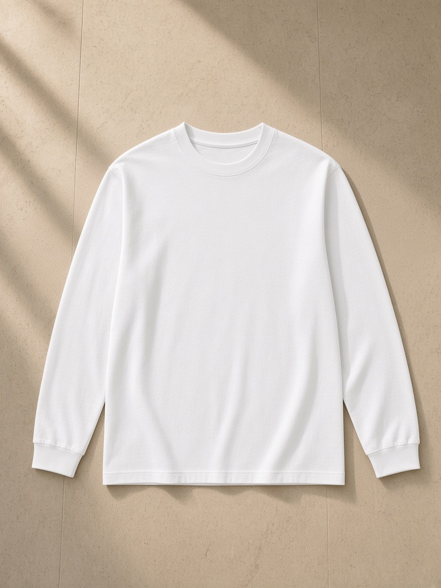 Crew neck drop shoulder long sleeve shirt in Basic White, laid flat on pale limestone
