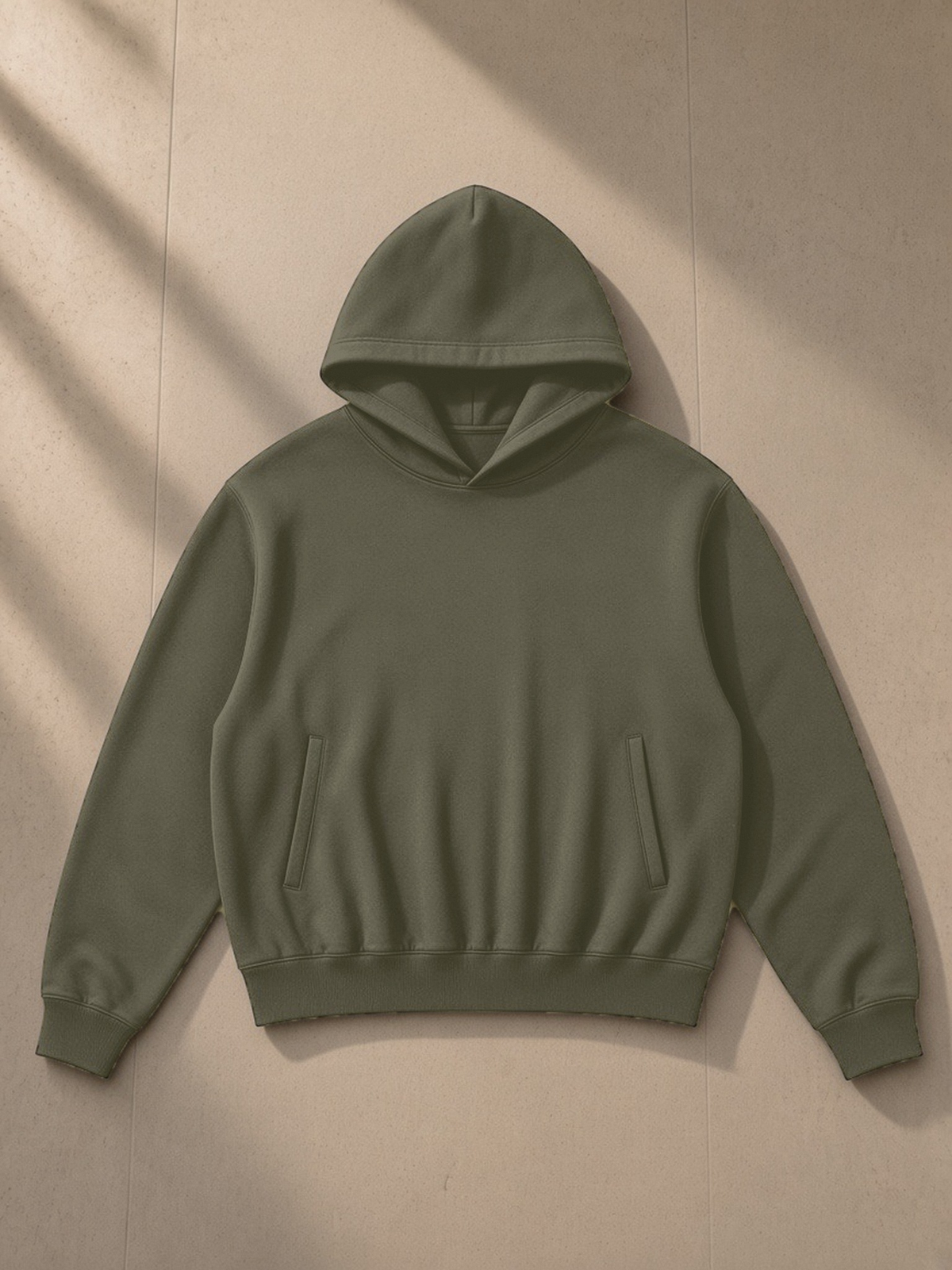 Oversized Drop Shoulder Hoodie in Army Green, laid flat on pale limestone, front view