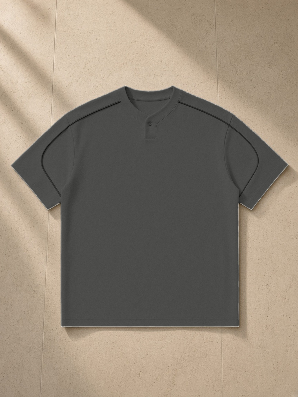 Oversized Piping Henley T-Shirt in Dark Gray, laid flat on pale limestone, front.