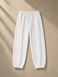 Essential Jogged Sweatpants in White, laid flat on pale limestone