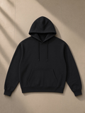 Relaxed Fit Hoodie in Black, laid flat on pale limestone