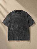 Unisex heavyweight snow washed t-shirt in Batik Black, laid flat on pale limestone