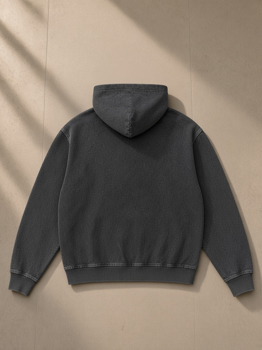 Unisex snow wash oversized zip-up hoodie in Black, laid flat on pale limestone, back view