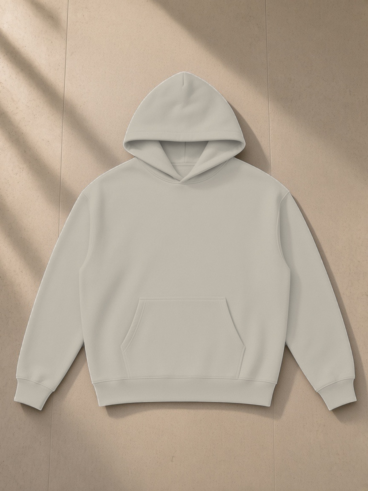 Essential Heavyweight Hoodie in Light Gray, laid flat on pale limestone, front.