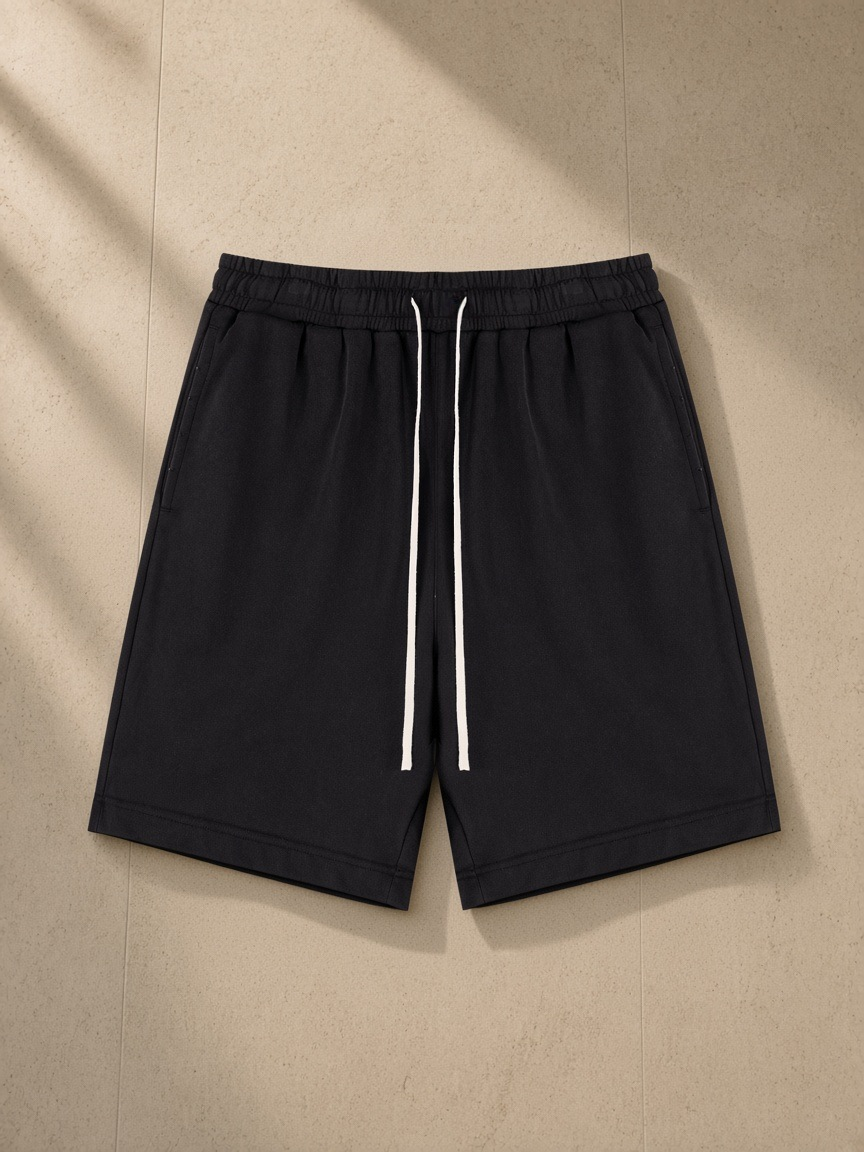 Drawstring shorts in Washed Black, laid flat on pale limestone