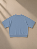 Unisex vintage wash boxy short sleeve sweatshirt in Blue, laid flat on pale limestone, back view