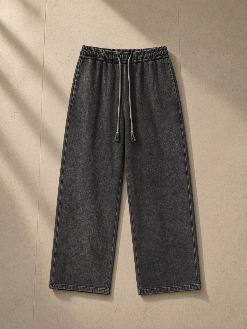 Snow Washed Straight Leg Pants in Black, laid flat on pale limestone