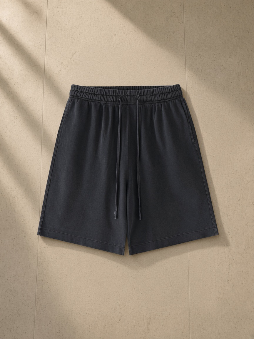 Vintage wash cotton shorts in Black, laid flat on pale limestone