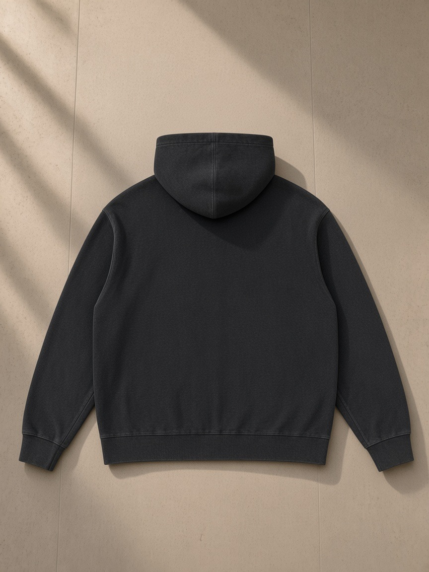 Mineral Wash Oversized Hoodie in Black, laid flat on pale limestone, back view