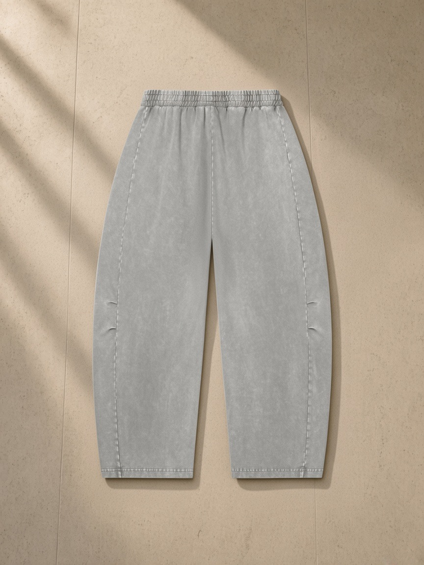 Unisex mineral wash barrel leg pants in Gray, laid flat on pale limestone, back view