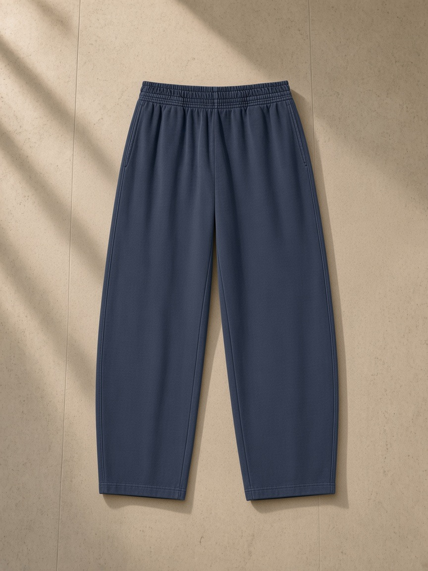 Vintage washed barrel leg sweatpants in Navy Blue, laid flat on pale limestone