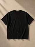 Unisex vintage wash distressed t-shirt in Black, laid flat on pale limestone