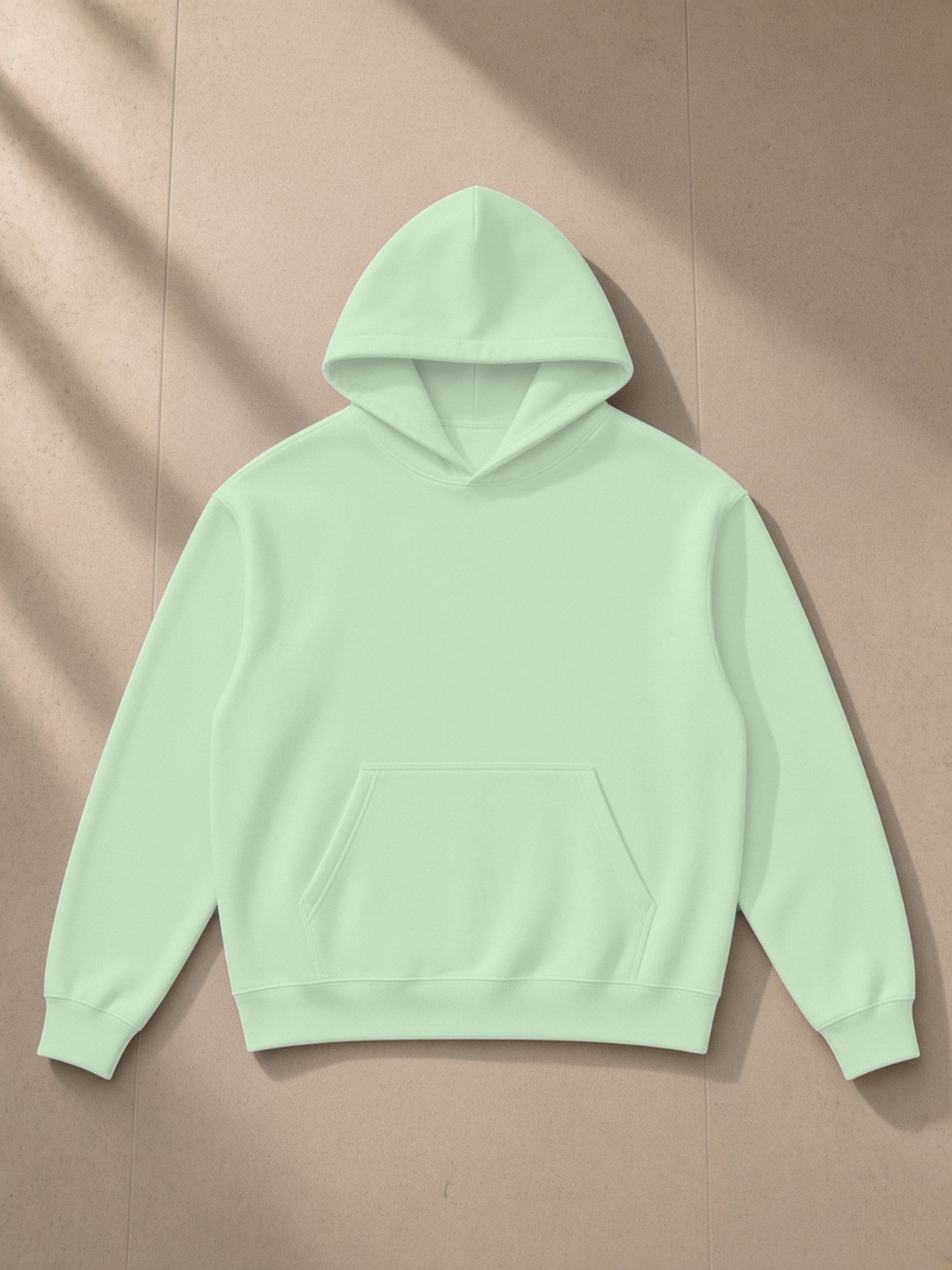 Essential Heavyweight Drop-Shoulder Hoodie in Light Green, laid flat on pale limestone, front.