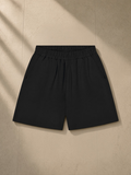 Unisex regular fit shorts in Black, laid flat on pale limestone