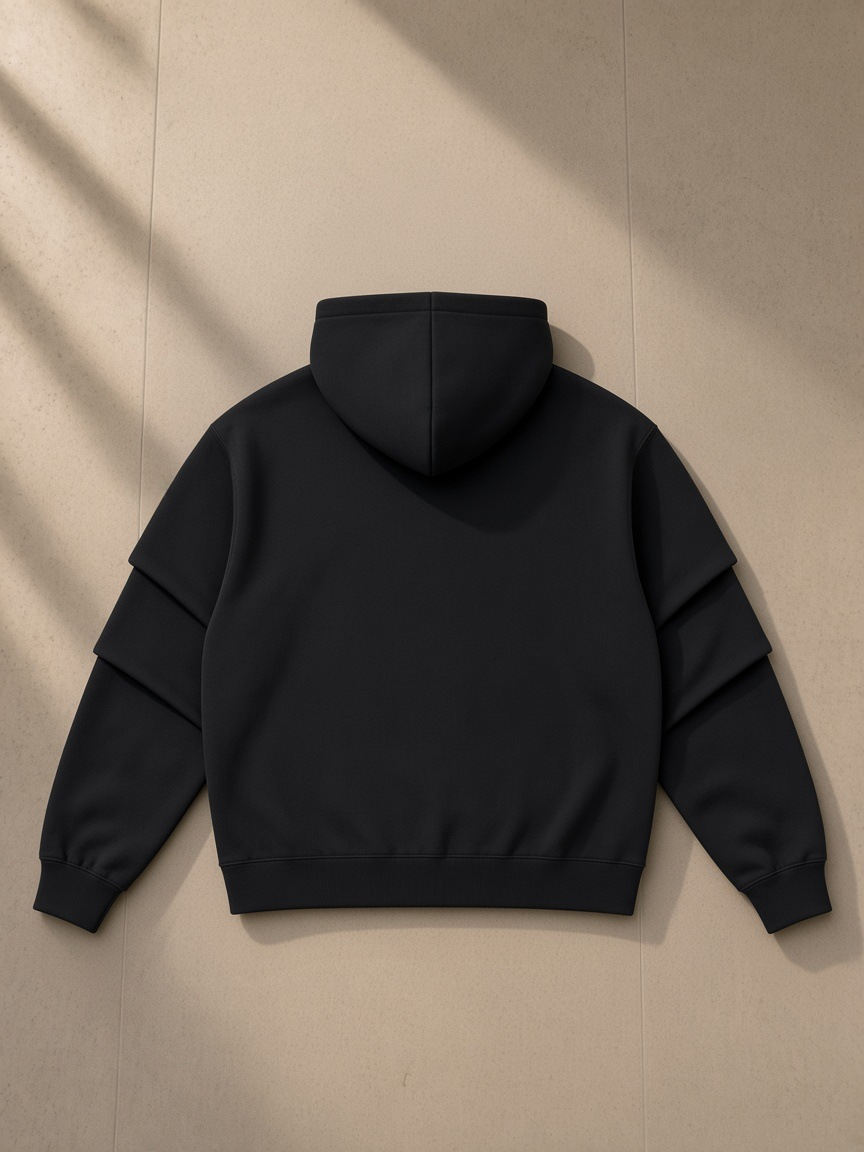 Unisex heavyweight ruched sleeves hoodie in Black, laid flat on pale limestone, back view