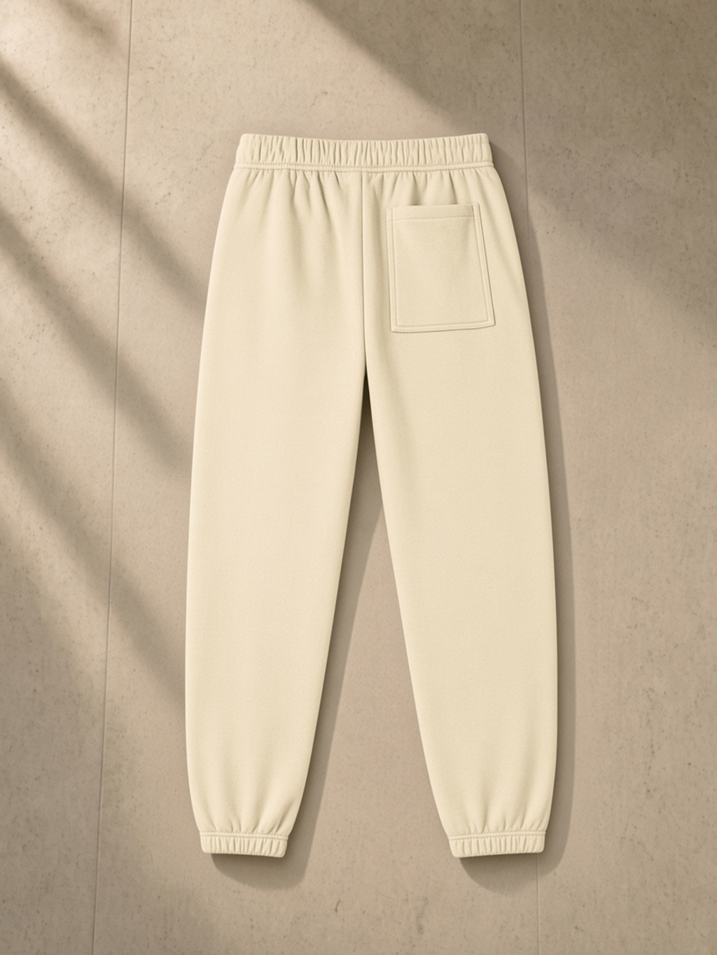 Essential Fleece Sweatpants in Apricot, laid flat on pale limestone, back.