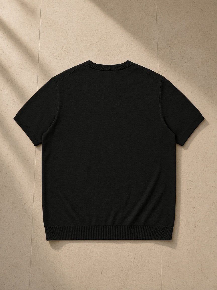 Crewneck Knit T-Shirt in Black, laid flat on pale limestone, back view
