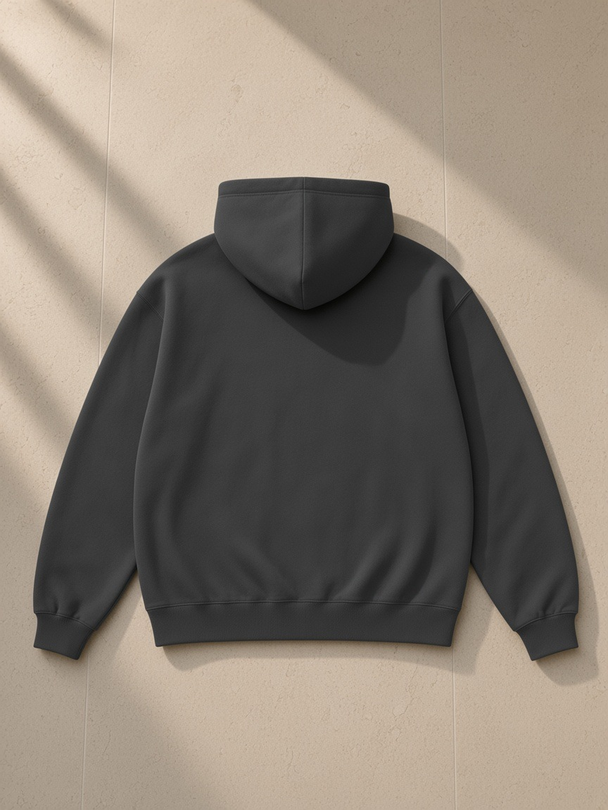 Unisex oversize heavyweight fleece hoodie in Charcoal, laid flat on pale limestone, back view