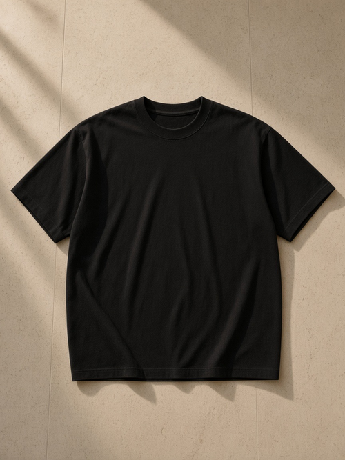 Unisex boxy Coolmax t-shirt in Black, laid flat on pale limestone