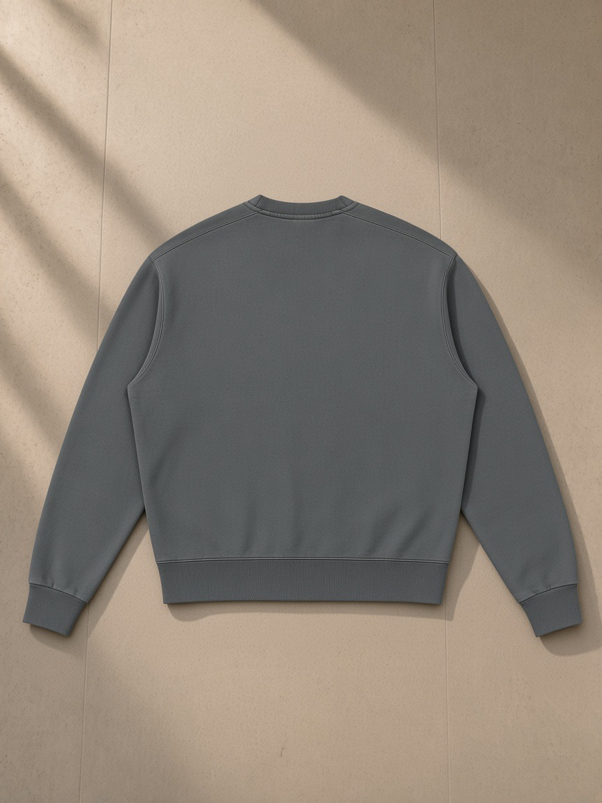 Unisex vintage wash crewneck sweatshirt in Dark Gray, laid flat on pale limestone, back view