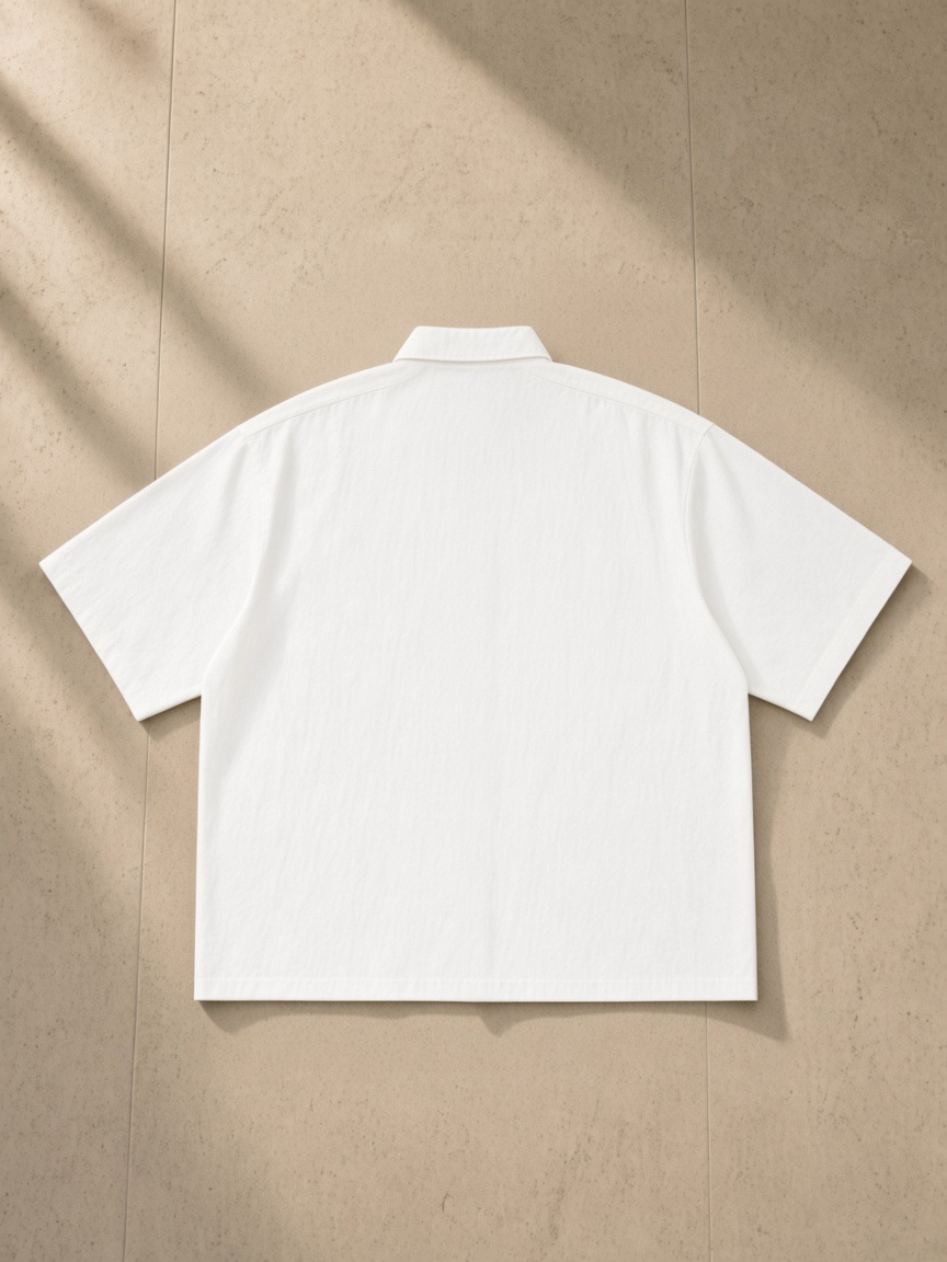 Boxy Heavyweight Short Sleeve Shirt in White, laid flat on pale limestone, back.