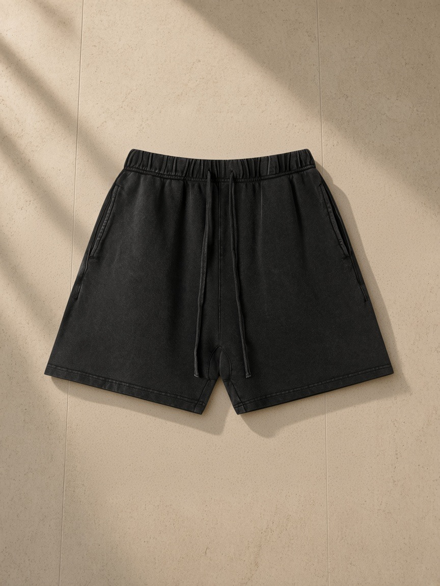Vintage Wash Cotton Shorts in Black, laid flat on pale limestone
