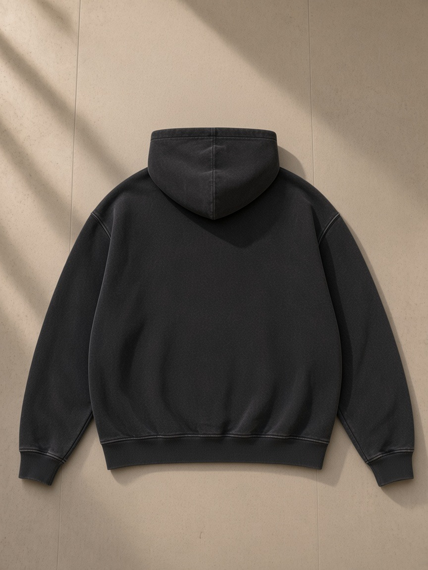 Snow Wash Fleece Oversize Hoodie in Black, laid flat on pale limestone, back view
