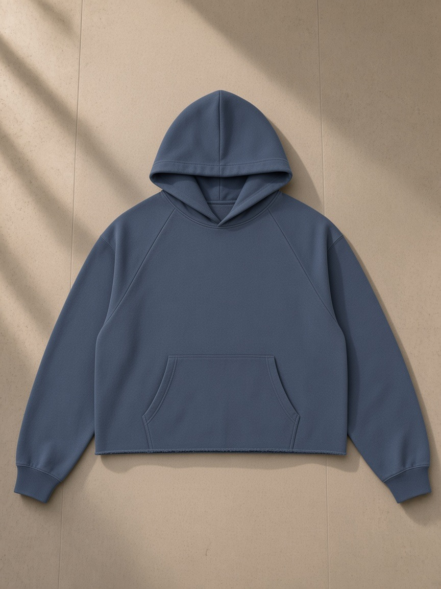 Vintage wash raw edge boxy hoodie in Blue, laid flat on pale limestone