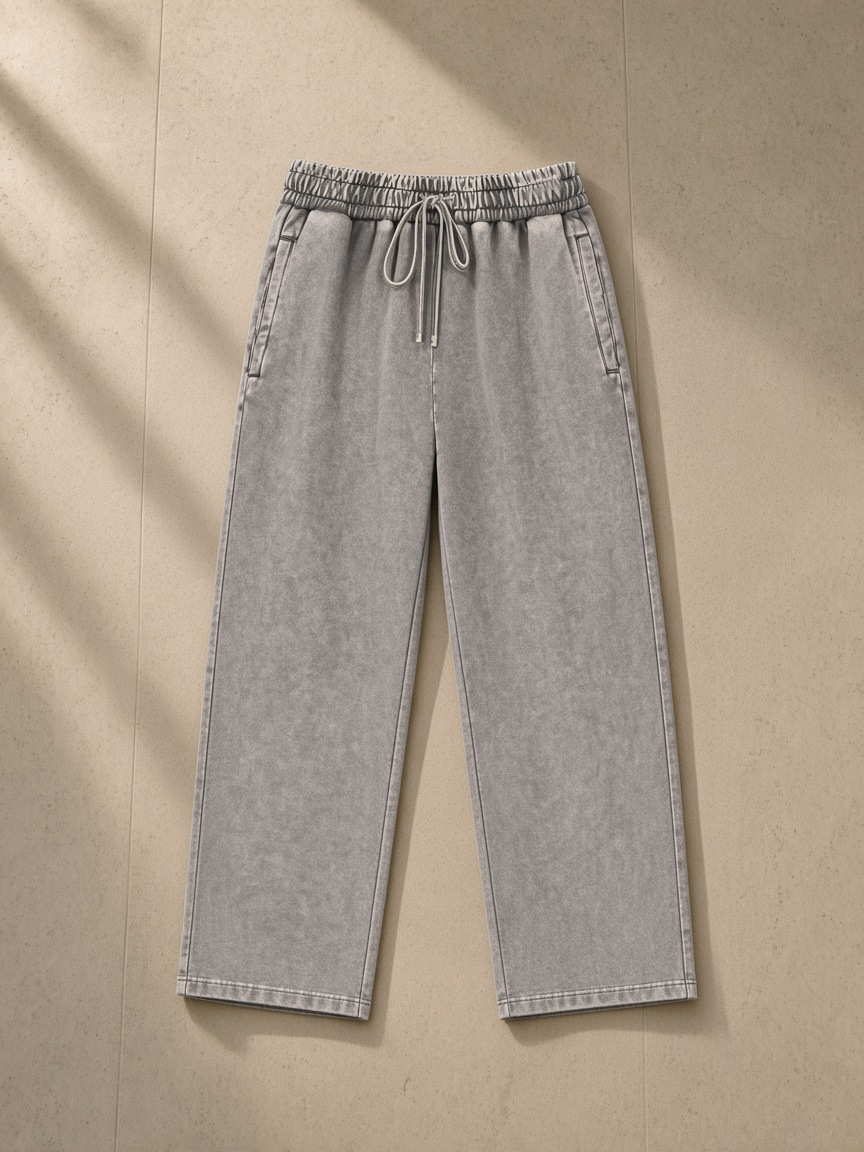 Unisex snow wash heavyweight sweatpants in Light Gray, laid flat on pale limestone