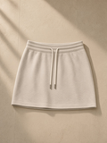 Women's drawstring skirt in Oat Gray folded on a turned-down linen bed in a Marfa, Texas guesthouse at night