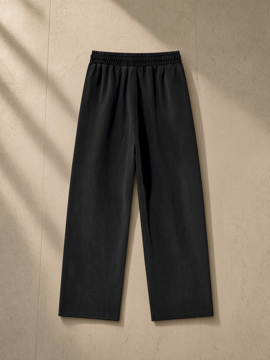 Heavyweight vintage wash sweatpants in Black, laid flat on pale limestone, back view
