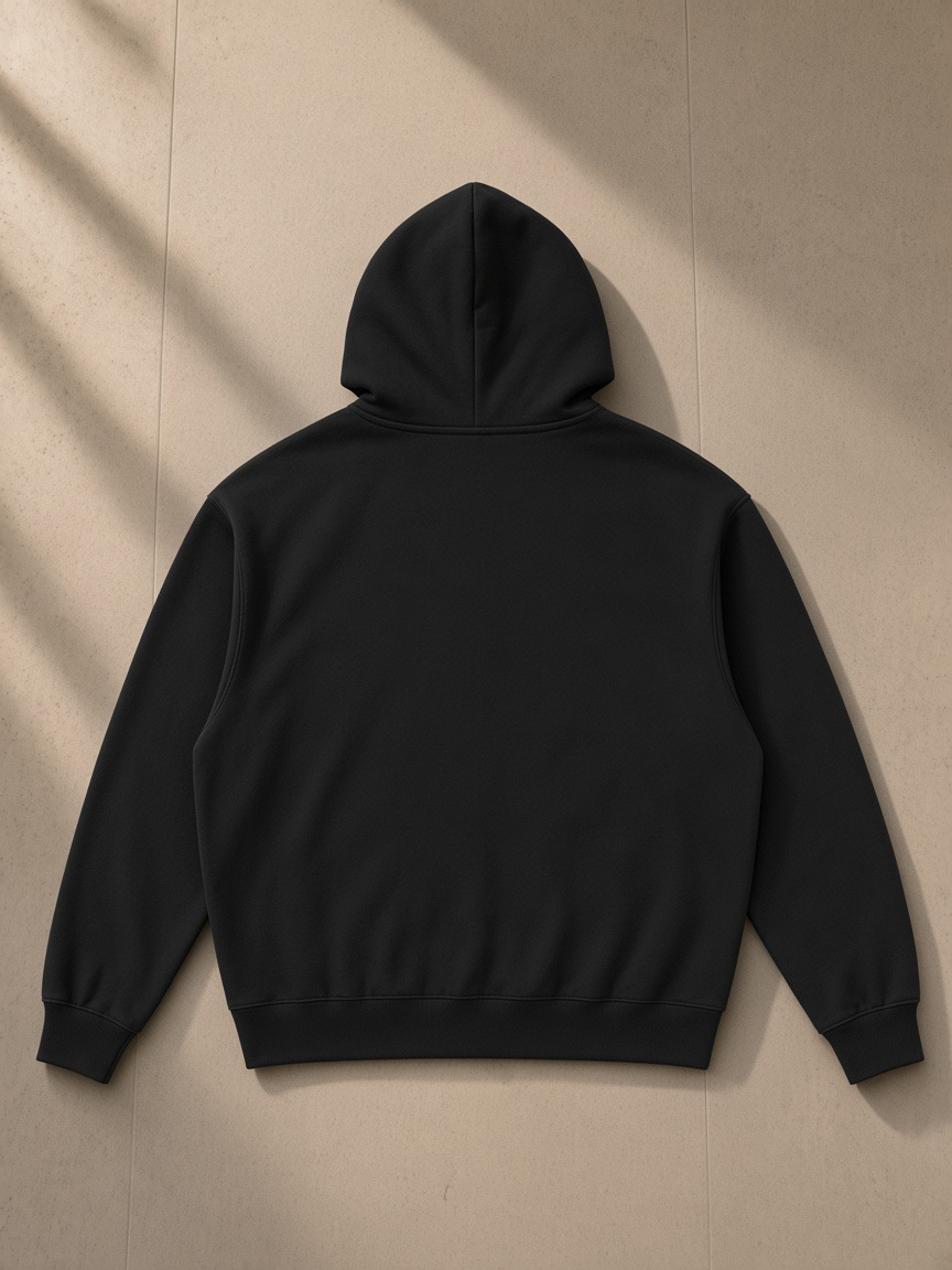Unisex loose full zip hoodie in Black, laid flat on pale limestone, back view