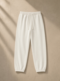 Essential Heavyweight Cotton Sweatpants in Apricot, laid flat on pale limestone