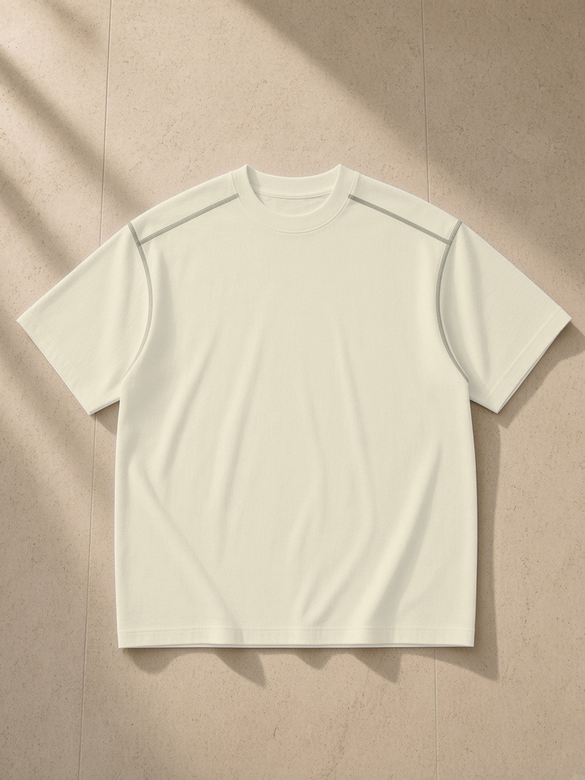 Oversized Contrast-Stitched Cotton Tee in Mild Apricot, laid flat on pale limestone, front.