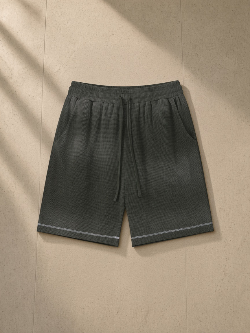 Sunfade waffle raw hem shorts in Gray Green, laid flat on pale limestone
