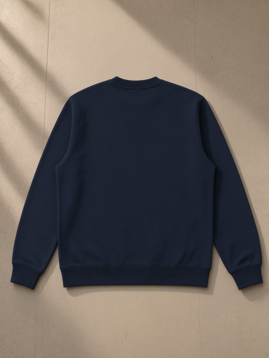 Unisex heavyweight crewneck sweatshirt in Dark Blue, laid flat on pale limestone, back view