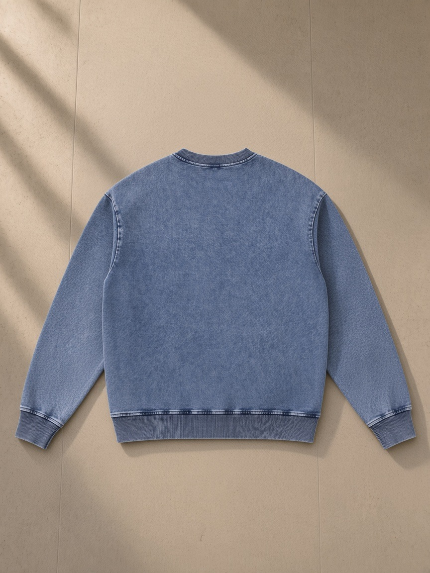 Unisex snow wash oversized crewneck sweatshirt in Light Blue, laid flat on pale limestone, back view