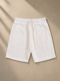 Essential Cotton Shorts in White, laid flat on pale limestone