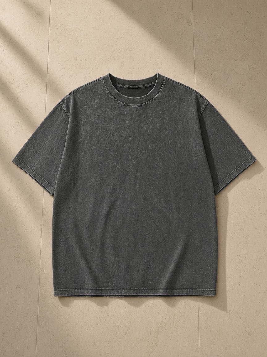 Unisex heavyweight snow washed t-shirt in Dark Gray, laid flat on pale limestone