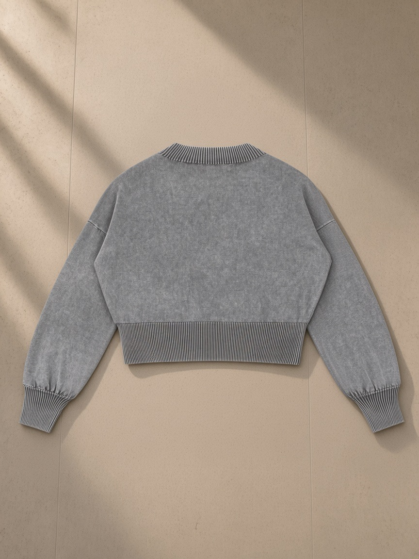 Women's Balloon Sleeve Cropped Sweater in Gray, laid flat on pale limestone, back view