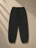 Fleeced Jogger Sweatpants in Black, laid flat on pale limestone